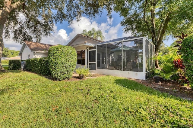 rear view of house with a lawn and a lanai