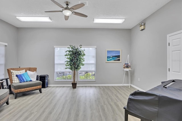 living area featuring a textured ceiling, ceiling fan, and light hardwood / wood-style floors