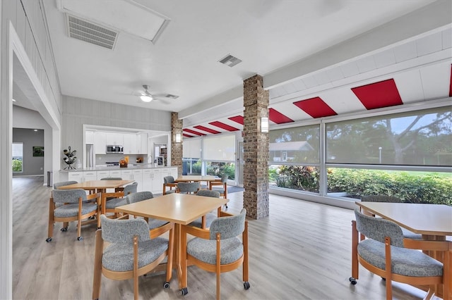 dining area with light wood-type flooring, ornate columns, and ceiling fan