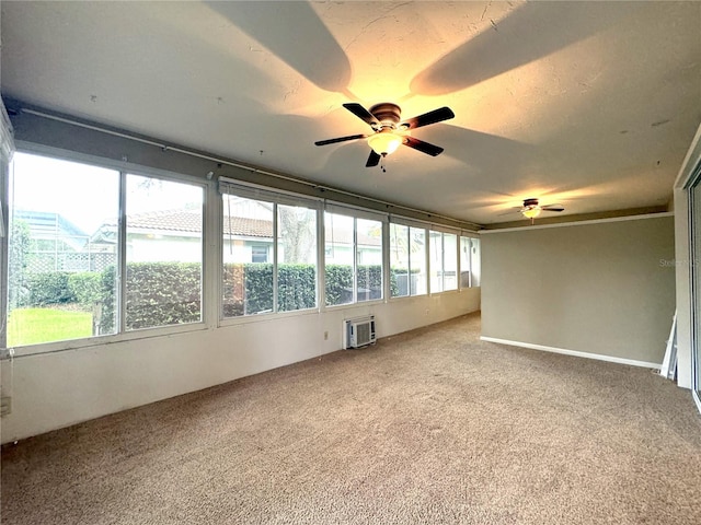 unfurnished room featuring a healthy amount of sunlight, ceiling fan, an AC wall unit, and carpet flooring