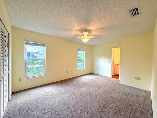 unfurnished bedroom featuring a textured ceiling, a closet, ceiling fan, and light carpet