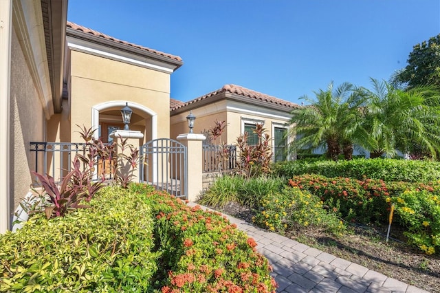 exterior space with a tiled roof, a fenced front yard, a gate, and stucco siding