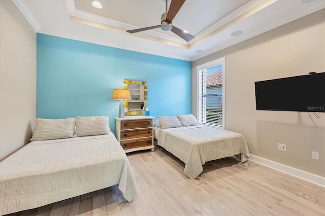 bedroom with ceiling fan, light hardwood / wood-style flooring, crown molding, and a raised ceiling