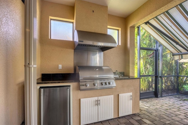 kitchen featuring sink, fridge, and wall chimney exhaust hood