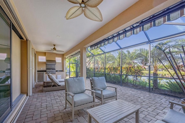 sunroom with ceiling fan and a water view