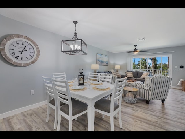 dining area featuring light hardwood / wood-style flooring and ceiling fan with notable chandelier