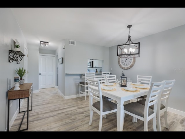 dining room with light hardwood / wood-style floors and a chandelier