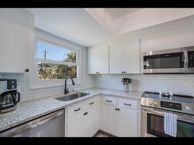 kitchen featuring sink, stainless steel appliances, white cabinetry, and tasteful backsplash