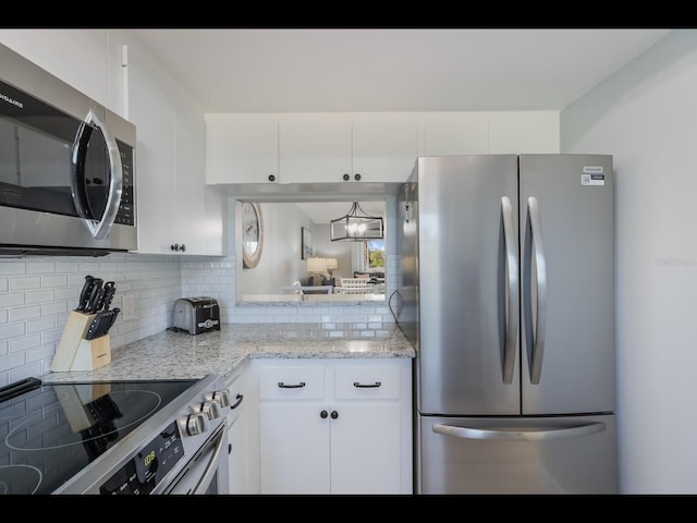 kitchen with appliances with stainless steel finishes, light stone counters, white cabinets, and backsplash