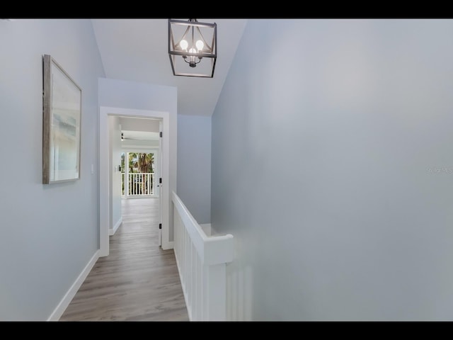 hall featuring wood-type flooring and a notable chandelier