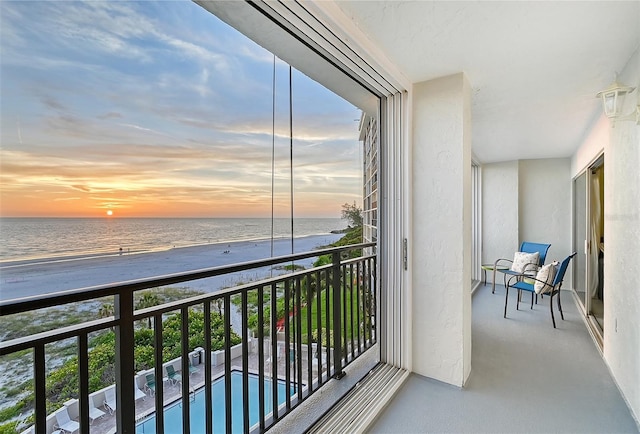 balcony at dusk with a view of the beach and a water view