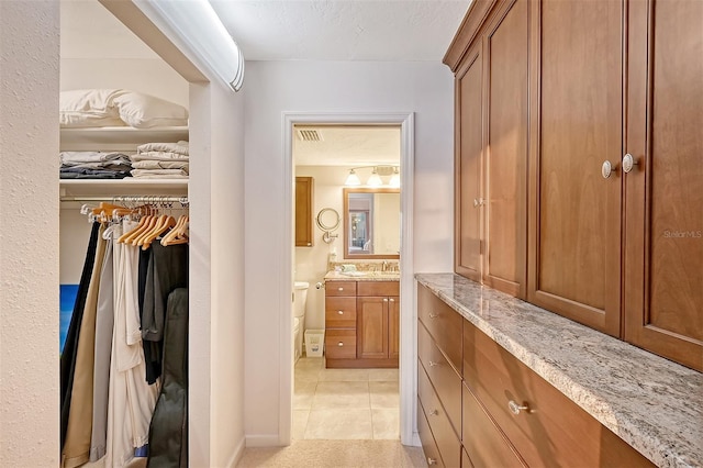 walk in closet with light tile patterned floors and sink