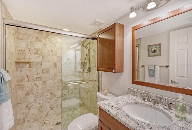 bathroom with a textured ceiling, vanity, toilet, and an enclosed shower