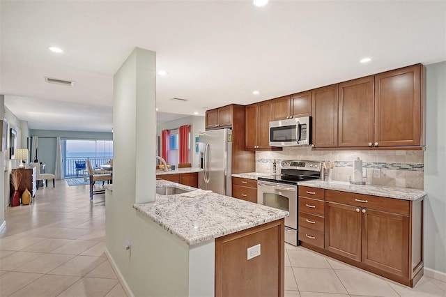 kitchen with light tile patterned floors, appliances with stainless steel finishes, light stone counters, sink, and decorative backsplash