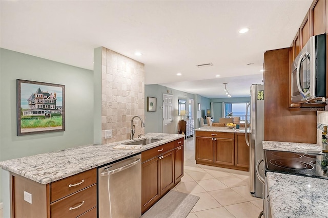 kitchen with light stone countertops, light tile patterned floors, appliances with stainless steel finishes, kitchen peninsula, and sink