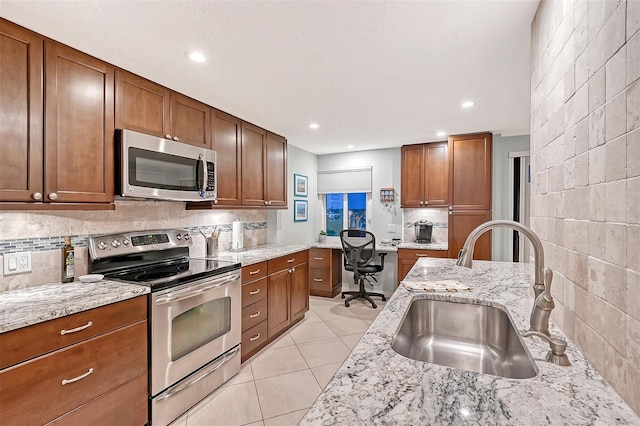 kitchen featuring light tile patterned floors, light stone counters, stainless steel appliances, and sink