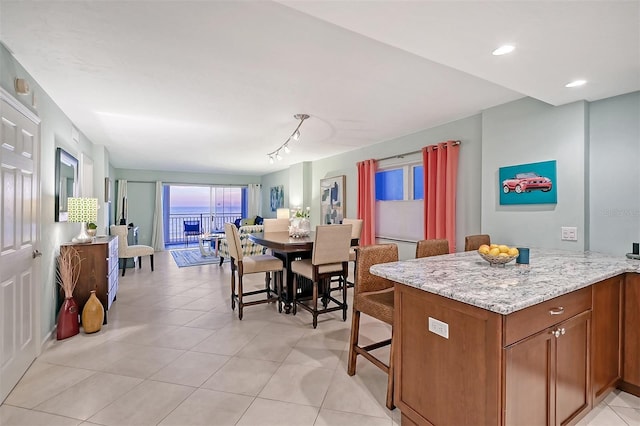 kitchen featuring light tile patterned flooring, kitchen peninsula, and light stone countertops