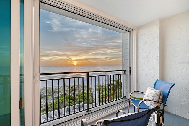 balcony at dusk featuring a water view