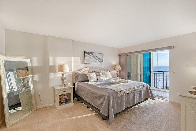 bedroom with light colored carpet, a water view, and access to outside