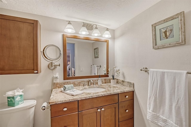 bathroom with toilet, a textured ceiling, and vanity