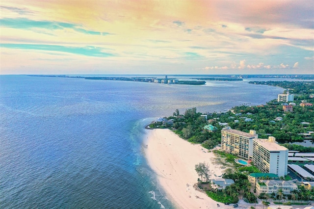 aerial view at dusk featuring a beach view and a water view