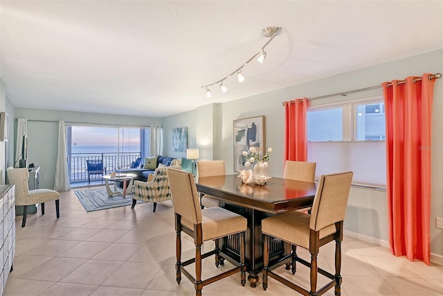 dining room with a water view, light tile patterned floors, and track lighting