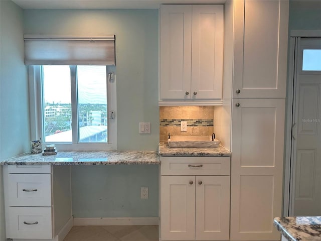 kitchen featuring white cabinetry, backsplash, and light stone counters