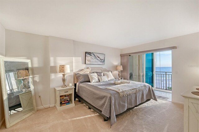 carpeted bedroom with access to exterior and a water view