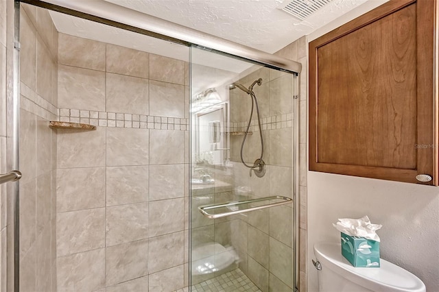 bathroom with a textured ceiling, toilet, and walk in shower