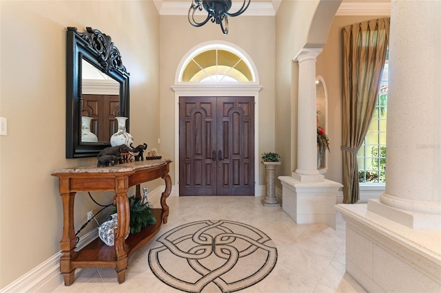 tiled entryway with a towering ceiling, decorative columns, and ornamental molding