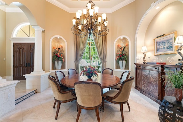 tiled dining room featuring a high ceiling, crown molding, an inviting chandelier, and decorative columns