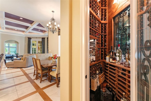 wine cellar with beam ceiling, coffered ceiling, an inviting chandelier, and light tile patterned floors