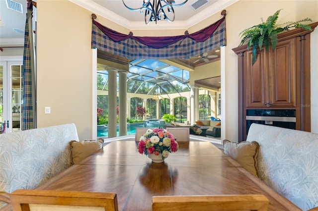 dining space with crown molding, a chandelier, and ornate columns