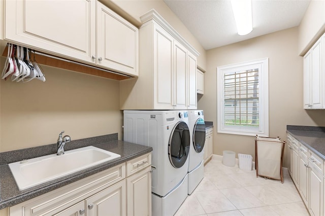 clothes washing area featuring sink, washer and clothes dryer, cabinets, and light tile patterned floors