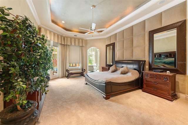 bedroom featuring ceiling fan, a raised ceiling, ornamental molding, and light carpet