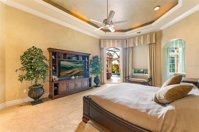 bedroom featuring ceiling fan, crown molding, light carpet, and a tray ceiling