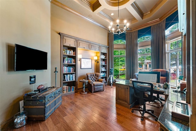 office space with a high ceiling, a notable chandelier, ornamental molding, wood-type flooring, and coffered ceiling