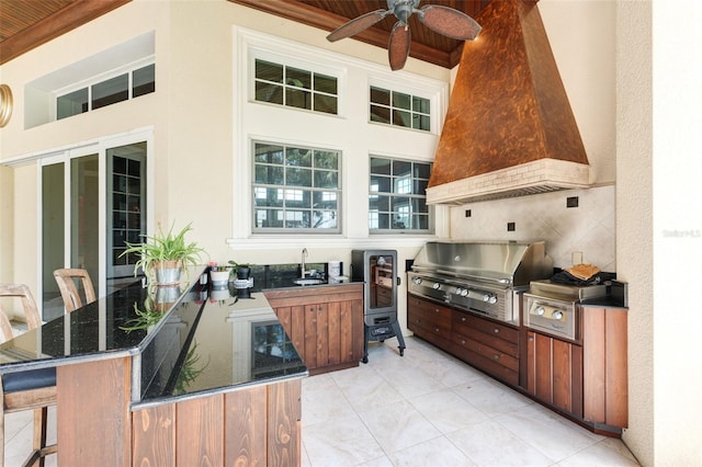 kitchen featuring premium range hood, sink, dark stone counters, kitchen peninsula, and ceiling fan