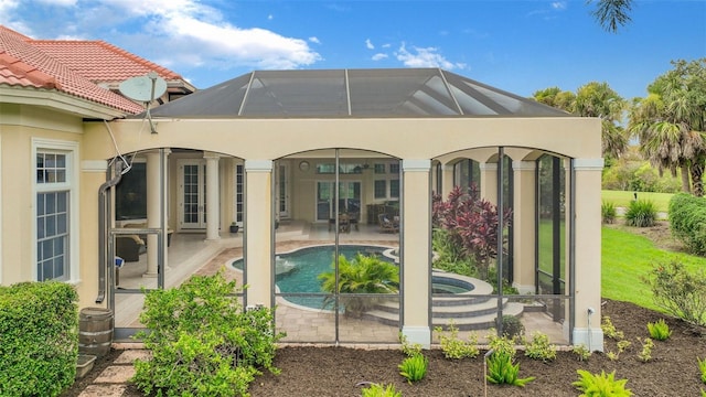 back of property with an outdoor pool, a patio, a lanai, and an in ground hot tub