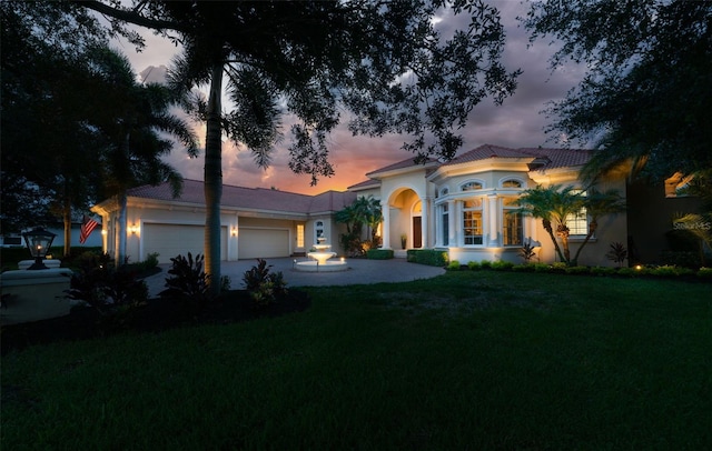 mediterranean / spanish-style house featuring a yard, an attached garage, and stucco siding