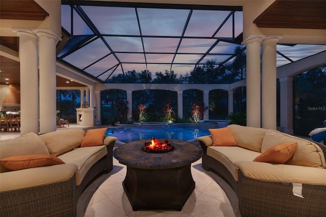 patio terrace at dusk with an outdoor living space with a fire pit, a pool with connected hot tub, and a lanai