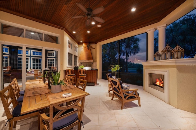 patio terrace at dusk with ceiling fan and an outdoor fireplace