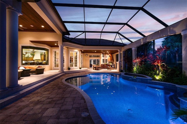 pool at dusk featuring a patio, an outdoor hangout area, a lanai, french doors, and a pool with connected hot tub