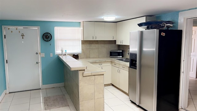 kitchen with light tile patterned flooring, stainless steel appliances, kitchen peninsula, and tasteful backsplash