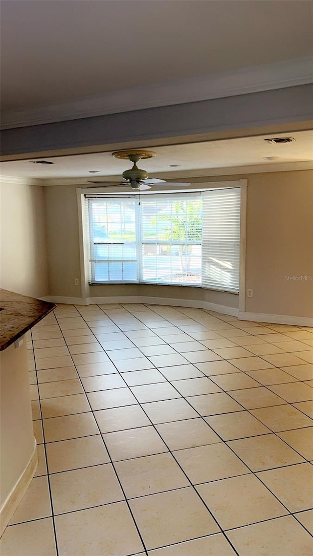 tiled empty room with ornamental molding and ceiling fan