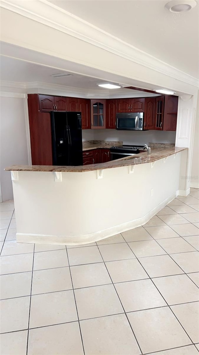 kitchen with light tile patterned flooring, a kitchen bar, kitchen peninsula, and black appliances