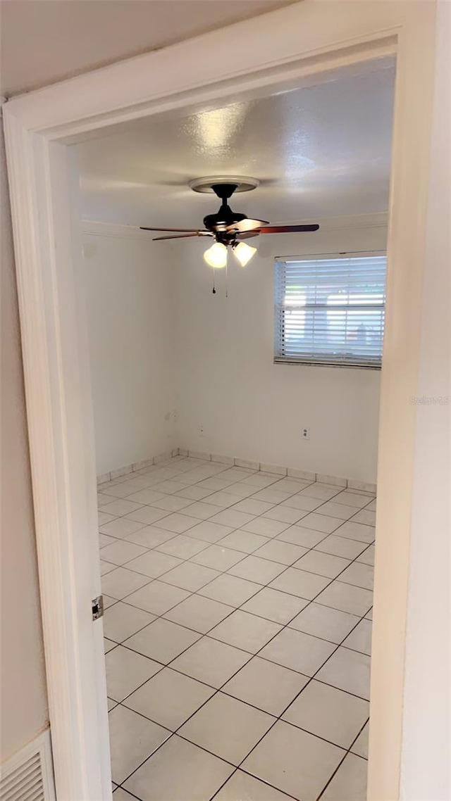 tiled spare room featuring ceiling fan