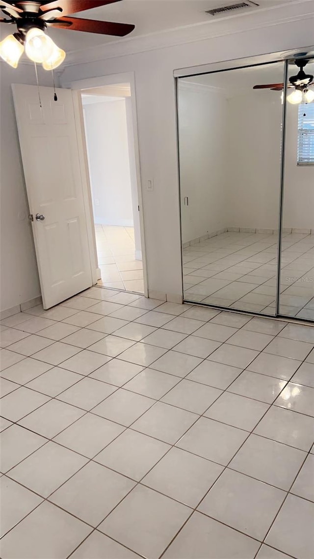 unfurnished bedroom featuring ornamental molding, a closet, ceiling fan, and light tile patterned flooring