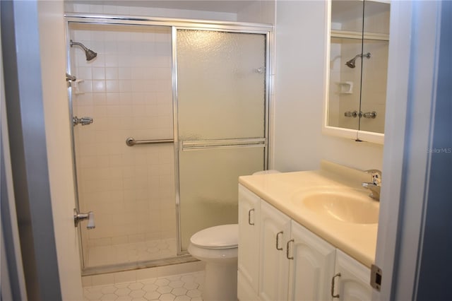 bathroom featuring tile patterned flooring, a shower with door, vanity, and toilet