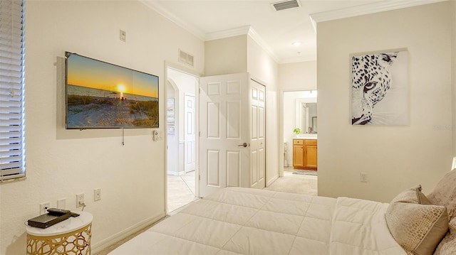 carpeted bedroom with crown molding and ensuite bath